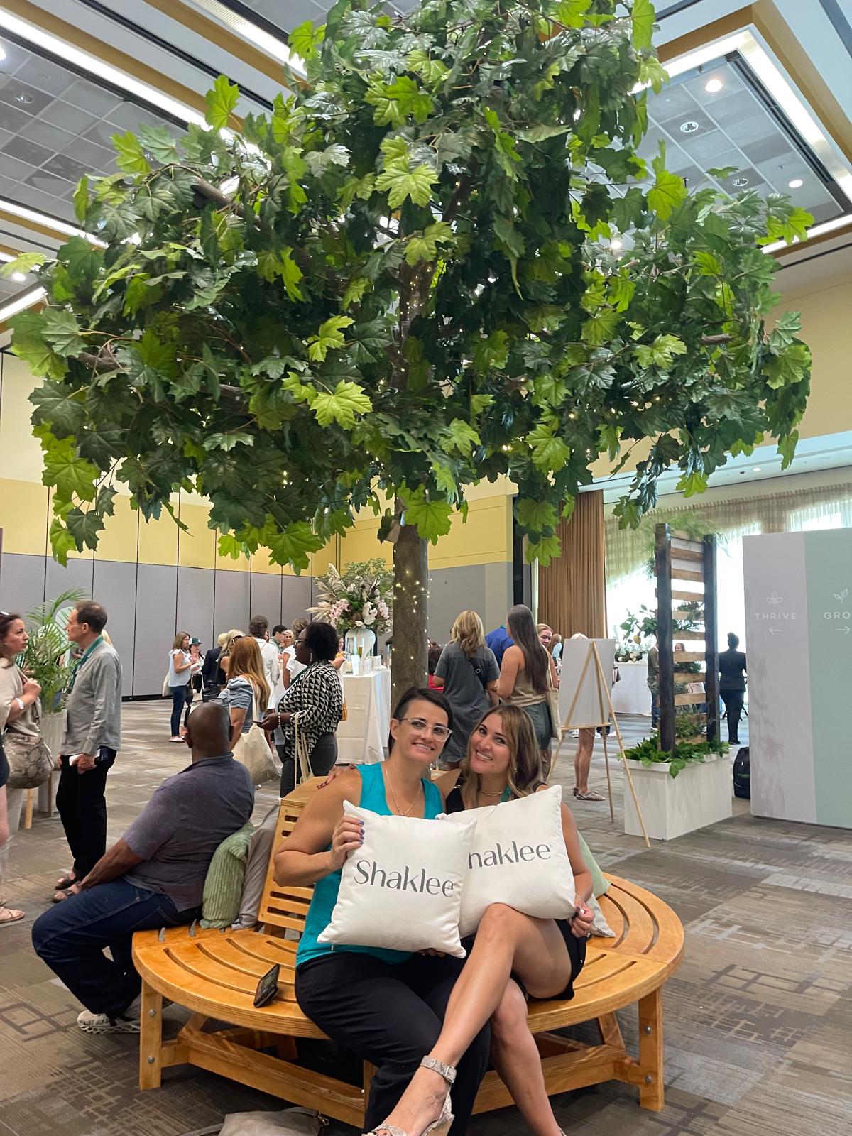 Regina posing with team member under a small tree