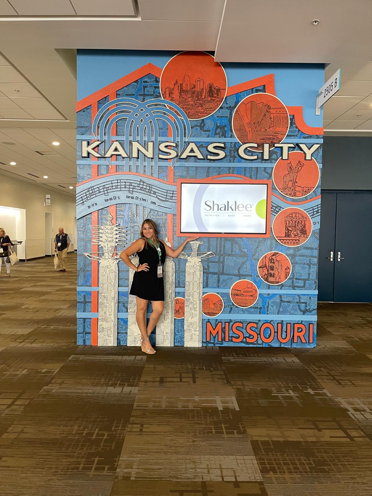 Regina posing Kansas City sign in airport